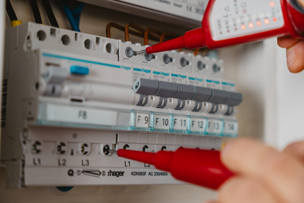 Elektriker prüft die Spannung an den Sicherungsautomaten einer elektrischen Unterverteilung